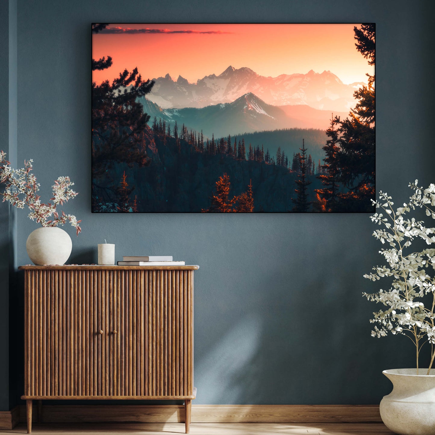 Massive horizontal nature photo of the sun setting over mountains hangs on blue wall in modern living room.