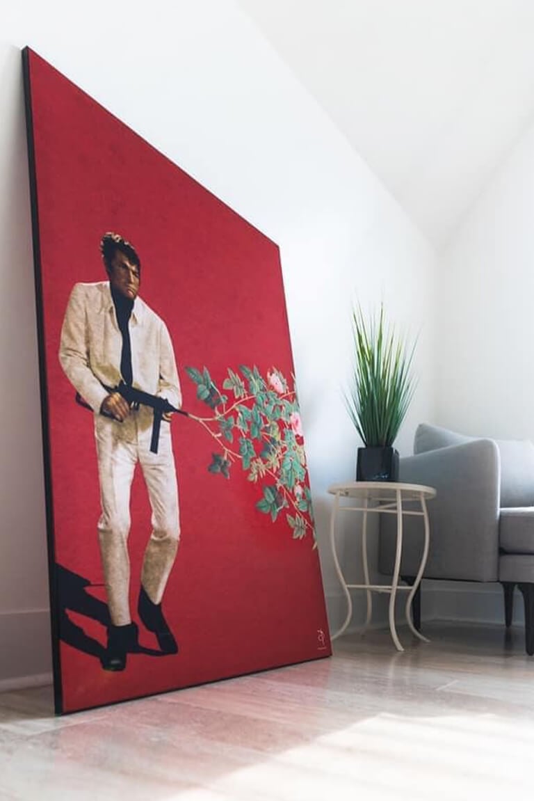 Massive red surreal artwork of man shooting gun with flowers exploding out leans up against wall in living room