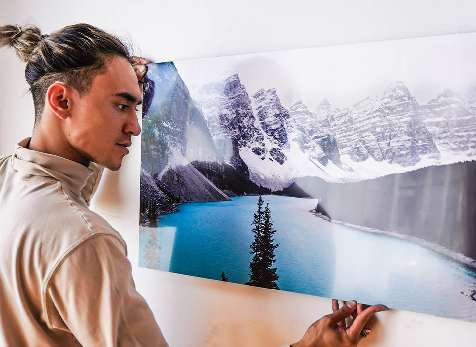 Man Hanging metal print of mountains on wall