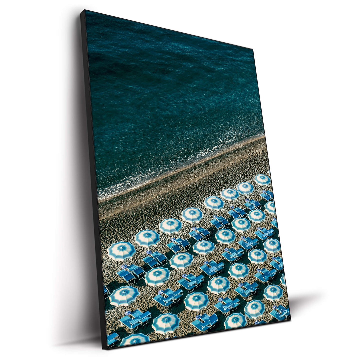 Overhead view of blue beach umbrellas on a sandy beach next to the ocean.