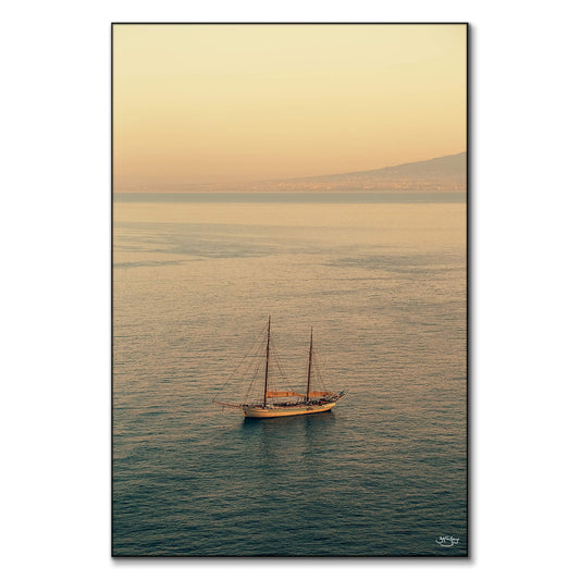 A sailboat on calm waters during a sunset in Italy.