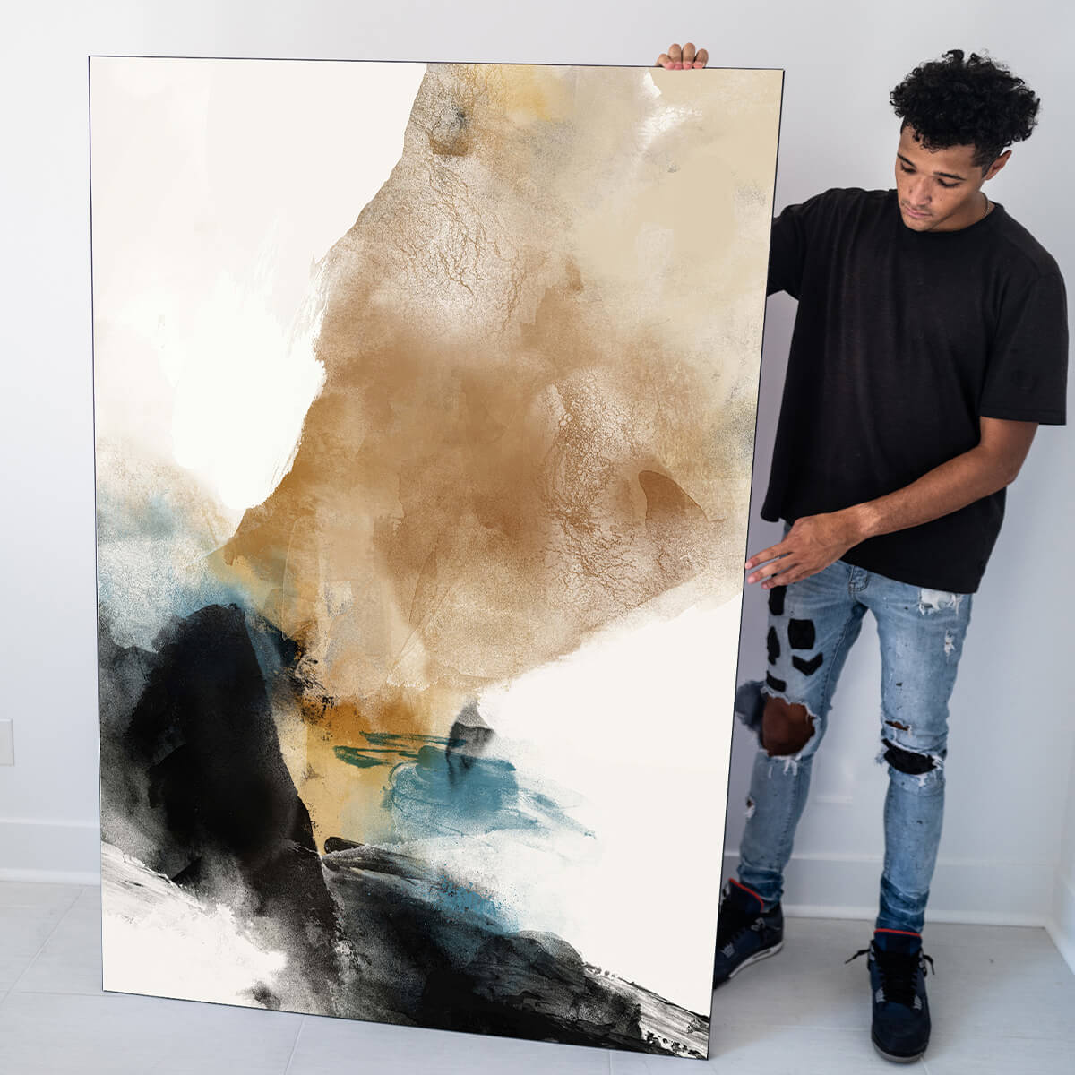 Wall art abstract being held in neutral living room by Black man. Big abstract art painting features tan, blue, white, and black.