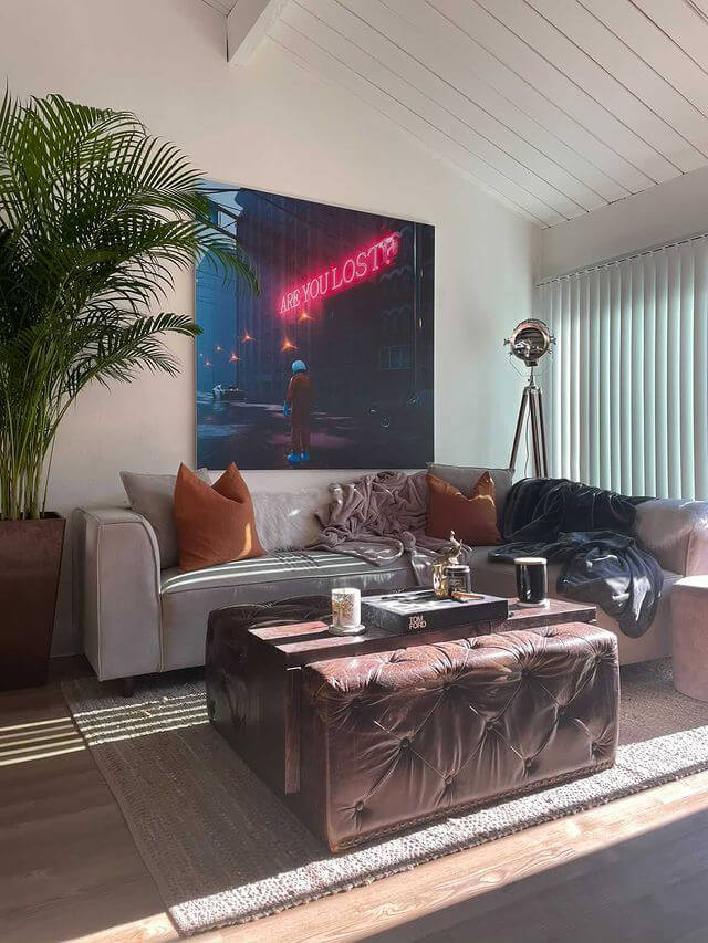 Large surreal art featuring astronaut and neon sign hangs above couch in living room.