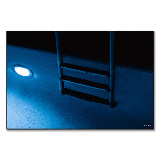 A blue pool at night, softly illuminated with reflections on the water.