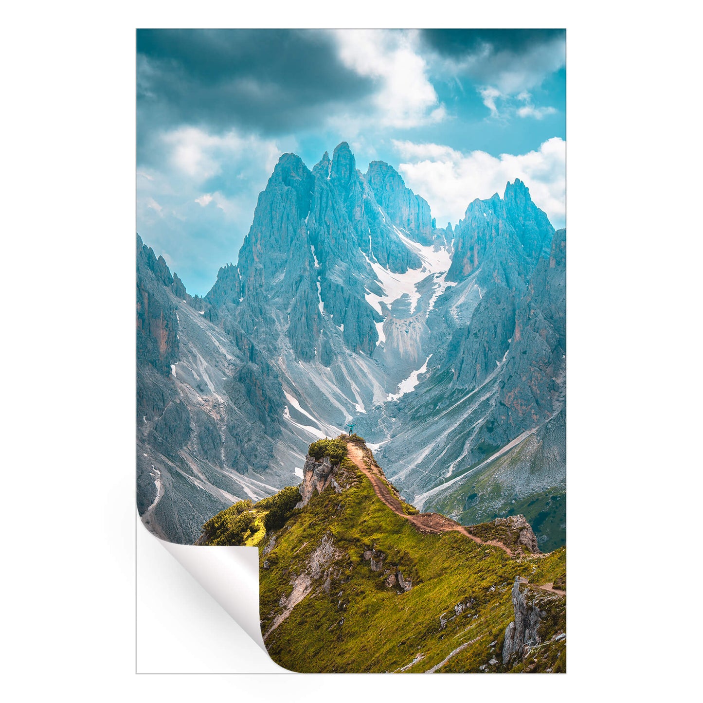 A person standing on a mountain peak, overlooking a vast and rugged landscape of valleys and peaks.