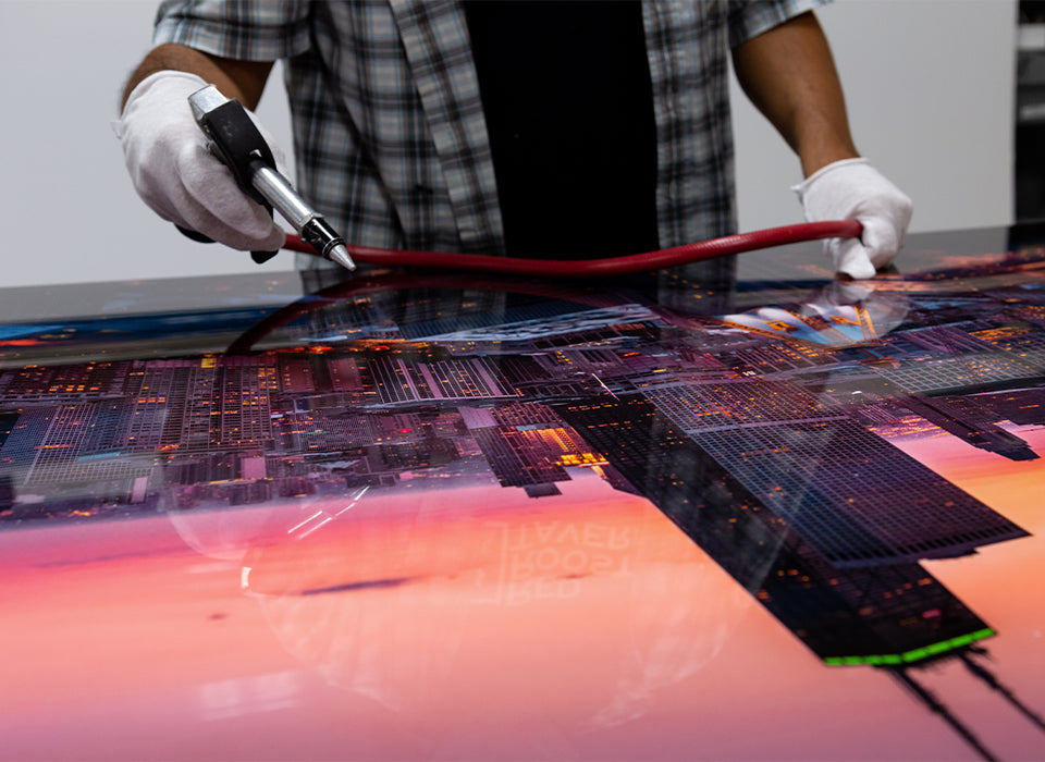 Person working on a metal print with a tool, focusing on the reflection