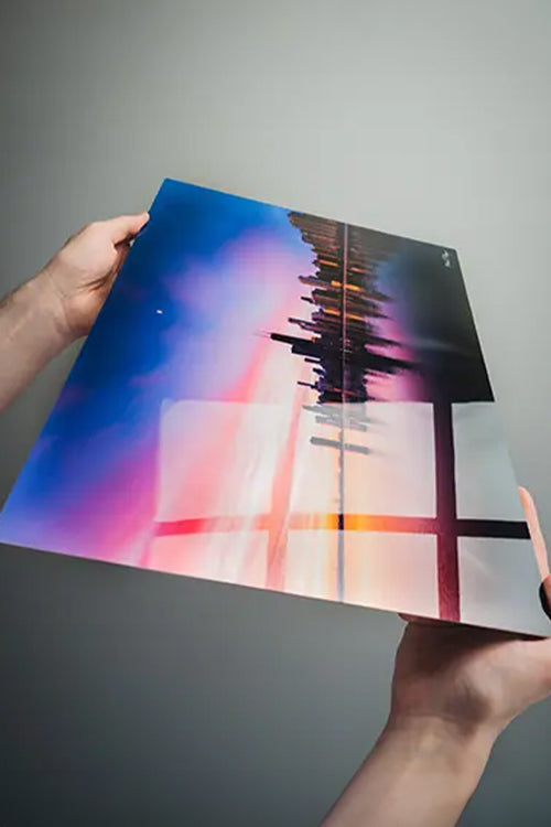Person holding a colorful abstract metal art print against a gray background loading=