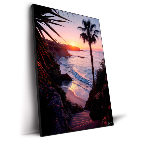 Sunset over water with a hidden staircase leading to a private beach, framed by palm trees and tropical plants.