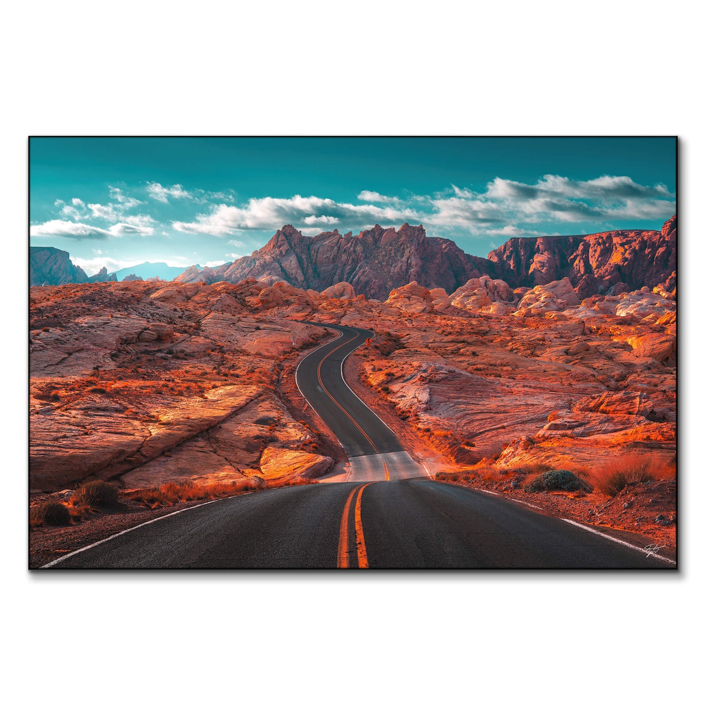 Winding road through the Valley of Fire in Nevada, with rugged mountains and a turquoise sky.