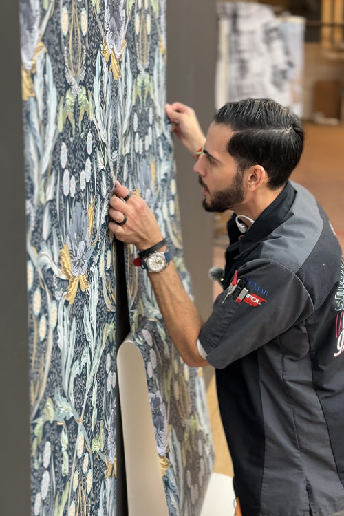 Man installing a wallpaper panel with a detailed pattern loading=