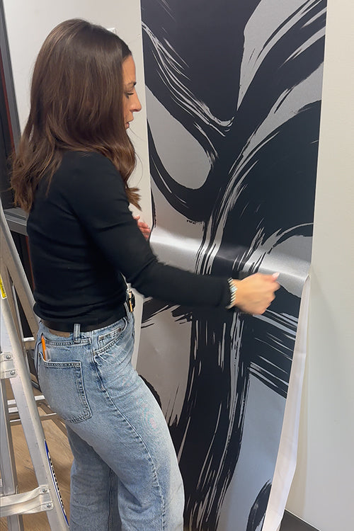Person applying decorative wall paper to a wall loading=