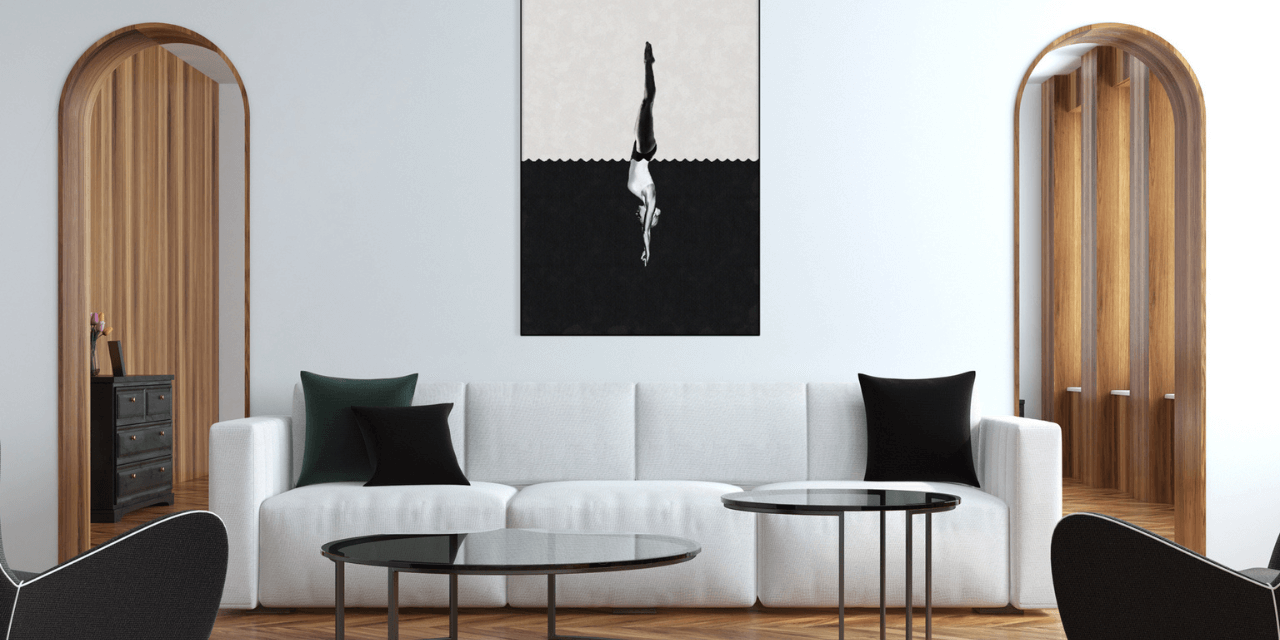 Colorful living room with pink walls, green velvet chairs, a brown leather sofa, and a black and white geometric artwork above a black fireplace.