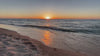 A wide cinematic shot of lake michigan at sunset, waves crashing on an empty beach.