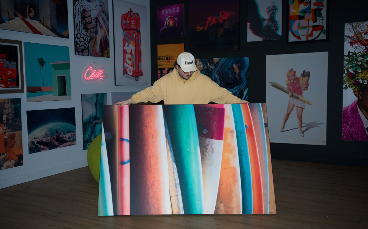 Person standing behind a colorful striped print with a vibrant wall of art in the background