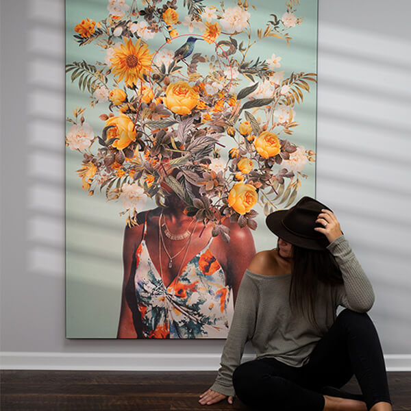 A woman sitting next to a Flower Head Wall Art by Frank Moth featuring floral surreal designs