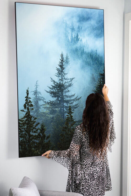 Extra Large Wall Art Featuring Fog Descending Over Ever Green Forest Being Hung in Neutral Living Room