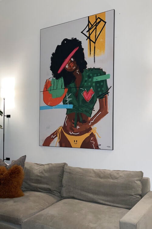 Colorful graffiti pop wall art of Black woman painted wearing yellow bikini and green crop top hangs in neutral living room