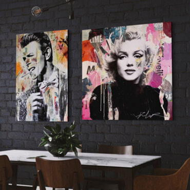 Pop singer wall art featuring David Bowie and Marilyn Monroe hang side by side on black brick wall in modern dining room