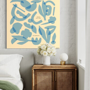 Massive light blue minimal wall art featuring layers of geometric shapes and flowers hangs on whitewashed brick wall above boho bed and side table.