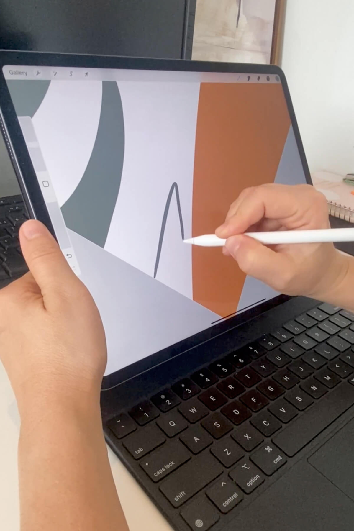 Close up shot of abstract artist Karine Tonial Grimm drawing leaf in green next to orange abstract shape using a white stylus on her iPad.