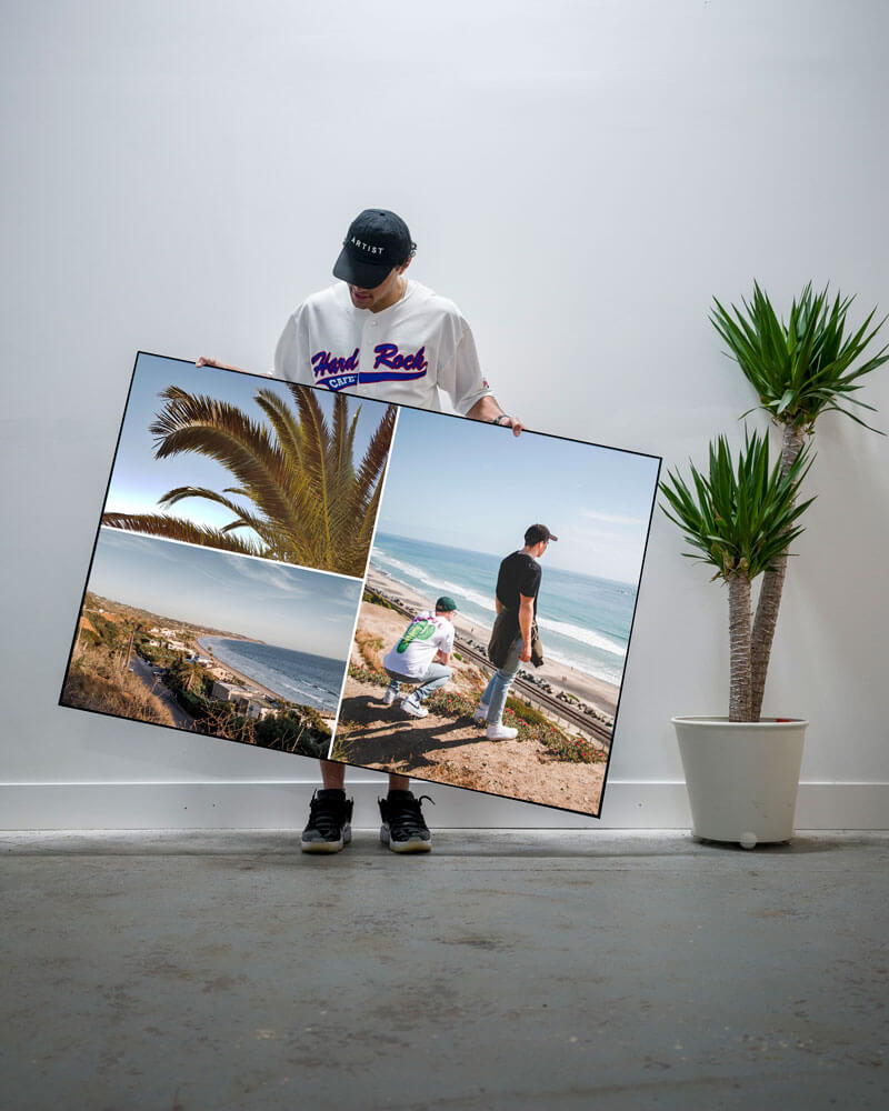 Man hold custom art print of beach photos from his phone in the living room of his apartment.