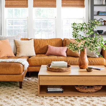 Warm and cozy living room with a leather sectional, textured rug, wood coffee table, and layered décor accents