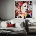 Bedroom image with a BIG Wall Decor piece of artwork on the Wall. The artwork is an abstract, street art, and pop art collage piece. It is mixed media with a celebrity model. There are other pops of red in this image including the red chair and red pillow to demonstrate the unexpected red theory.