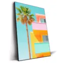 Modern building with pink, yellow, and turquoise colors, complemented by a tall palm tree, against a clear blue sky.