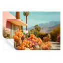 Modern pink house surrounded by vibrant orange and pink cacti, palm trees, and mountains under a blue sky.