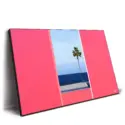 Palm tree framed by minimal pink walls with a blue sea and sky background.