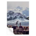 Cowboy with a horse in front of snow-capped mountains, surrounded by grazing horses in a tranquil landscape.