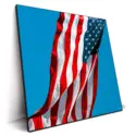 Photograph of the American flag waving in the wind against a clear blue sky.