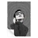 A woman in sunglasses poses in front of concentric black and white circles, creating a dynamic and fashionable artwork.