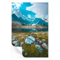 Clear mountain lake reflecting rugged terrain and towering peaks under a bright sky.