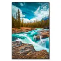 Rocky stream with aqua blue waters flowing over rocks, surrounded by trees and under a blue sky.