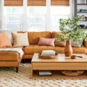 Warm and cozy living room with a leather sectional, textured rug, wood coffee table, and layered décor accents