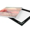 a piece of art showing a sunset laying on top of a picture frame.
