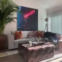 Large surreal art featuring astronaut and neon sign hangs above couch in living room.