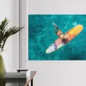 Surfer girl hanging perpendicular to her surf board deep in clear, blue ocean water