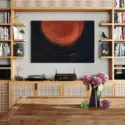 Large contemporary oil painting artwork in black and orange hangs horizontally in boho living room entertainment center in place of the TV.