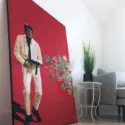 Massive red surreal artwork of man shooting gun with flowers exploding out leans up against wall in living room