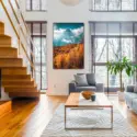 Massive nature photo of golden forest in the fall with mountain backdrop hangs in modern living room