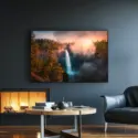 Large horizontal waterfall artwork hangs above fireplace in dark and moody modern living room.