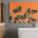 Extra large colorful bathroom wall art with palm trees on orange background hangs on light grey wall above soaking tub in bathroom.