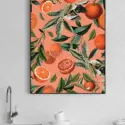 Large vertical orange fruit print hangs on white tile wall in kitchen above sink.