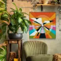 Large boho wall art in orange,yellow, black, white, blue, and green geometric circle hangs above green chair in a boho living room