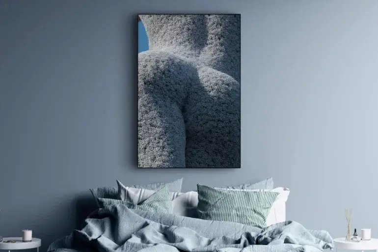 Oversized white flower wall art of hedge trimmed like woman's figure hangs above bed in blue bedroom.