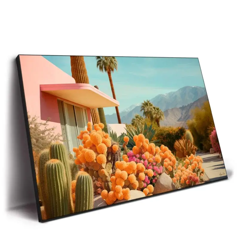 Pink house with pink facade surrounded by vibrant cacti, tall palm trees, and mountains under a clear blue sky.