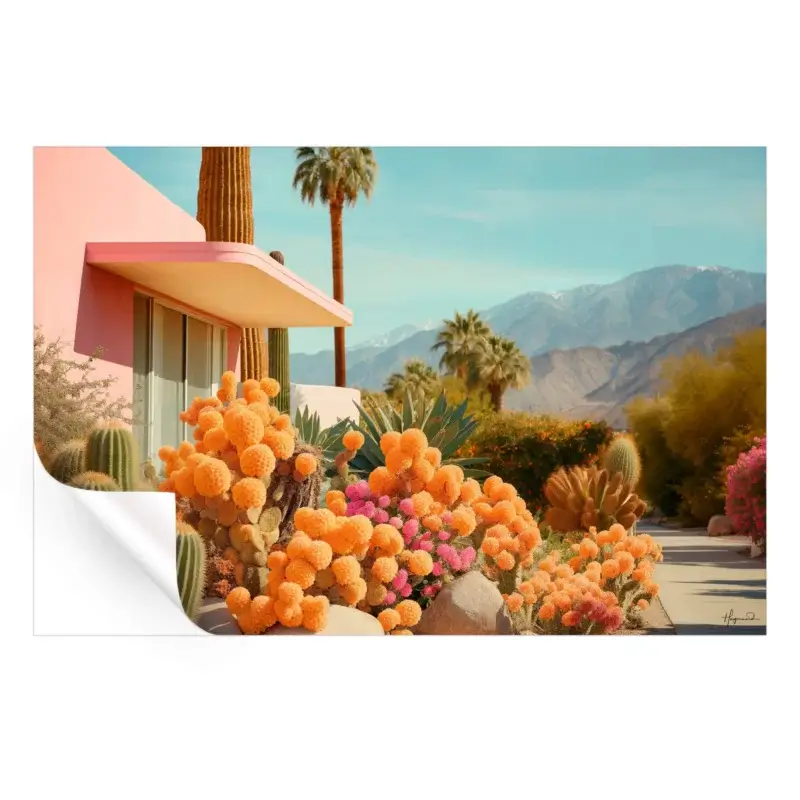 Modern pink house surrounded by vibrant orange and pink cacti, palm trees, and mountains under a blue sky.