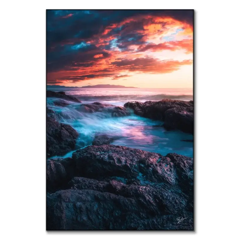 Sunset over the rugged coast of Tofino, British Columbia, with vibrant sky colors and crashing waves against dark rocks.